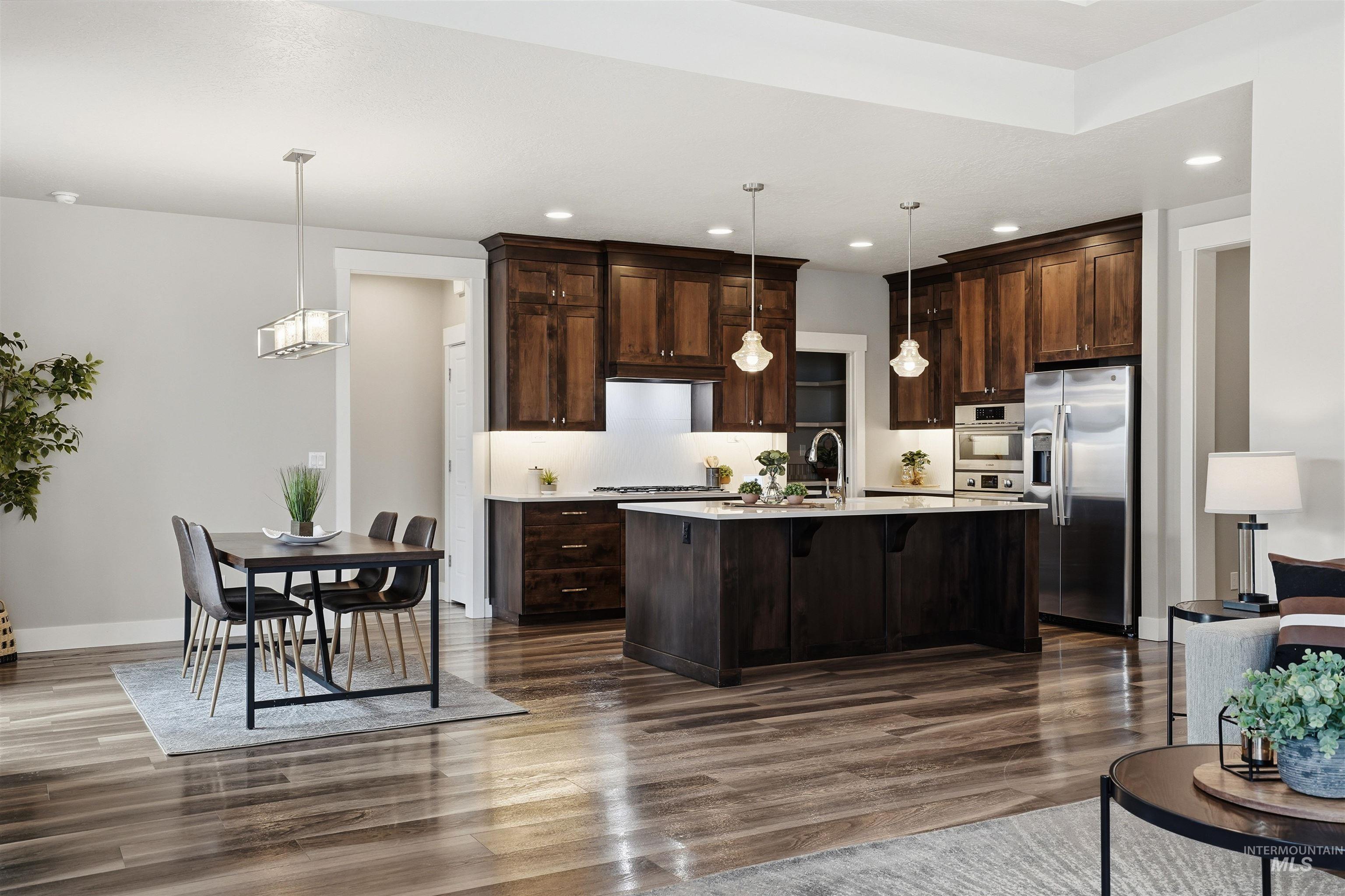 8087 Tandy Cove Street Middleton, ID 83644 - Photo 11 of 50 Kitchen featuring dark wood finish cabinetry, stainless steel appliances, a kitchen breakfast bar, and decorative light fixtures