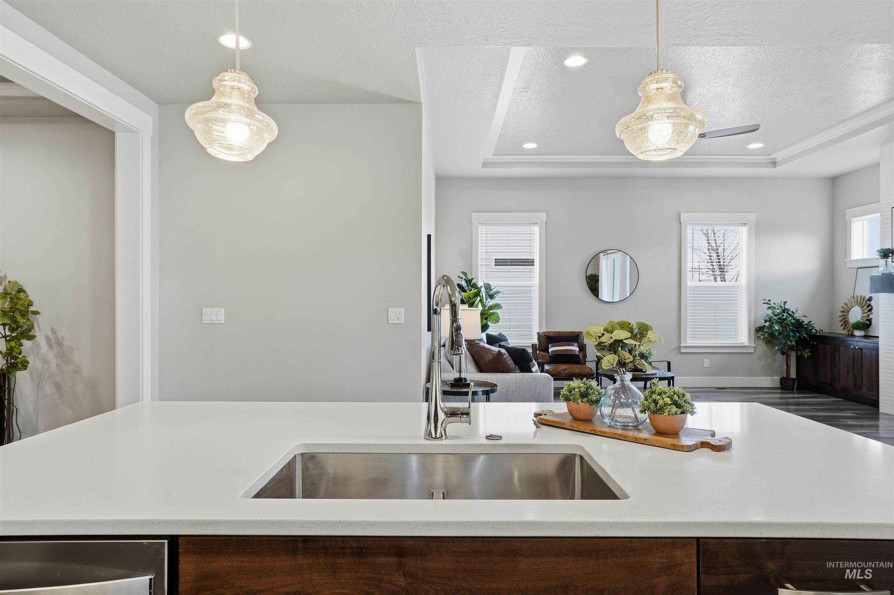8087 Tandy Cove Street Middleton, ID 83644 - Photo 50 of 50 Kitchen with a raised ceiling, dark wood finish cabinets, open floor plan, pendant lighting, and an island with sink