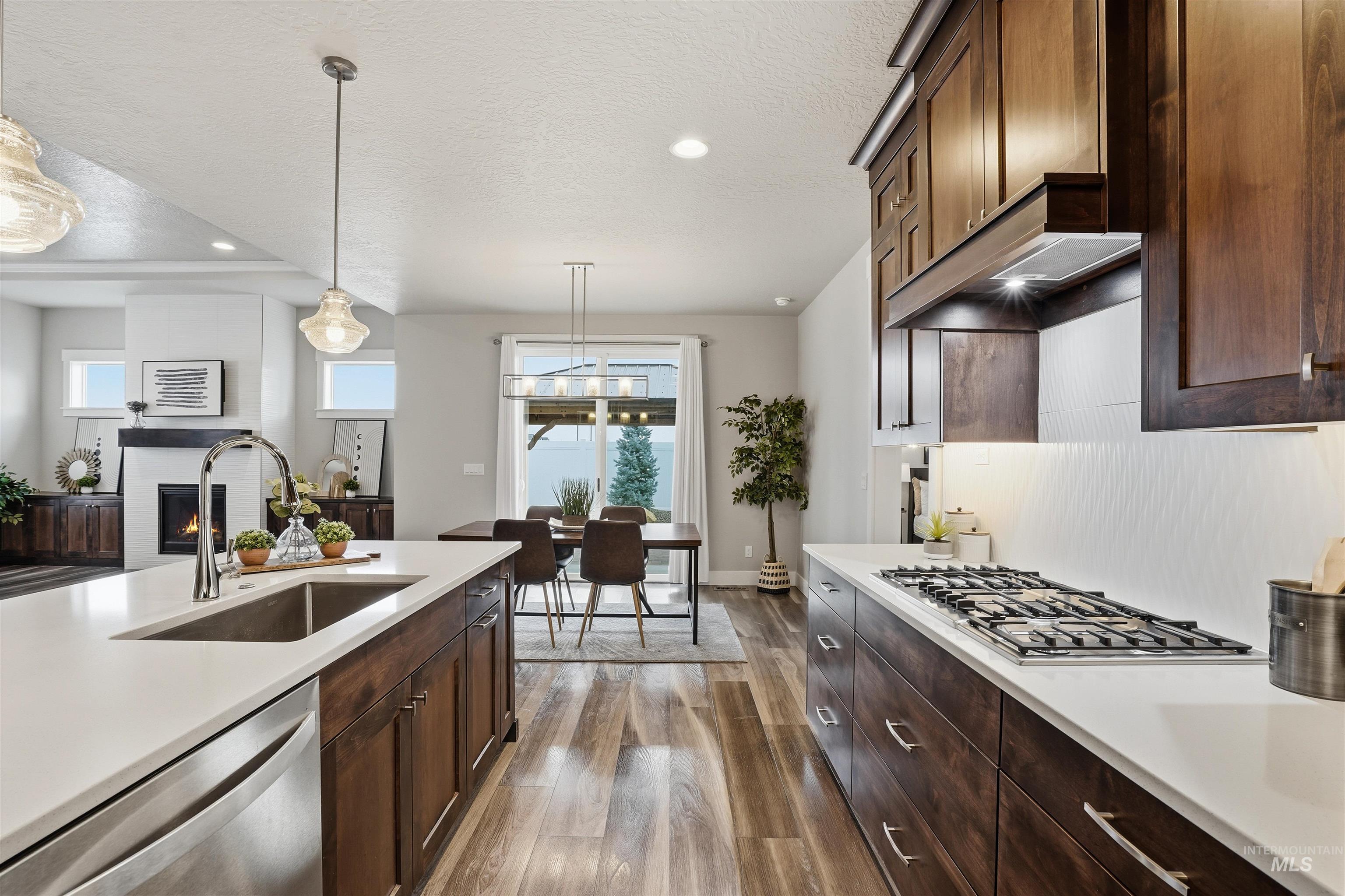 8087 Tandy Cove Street Middleton, ID 83644 - Photo 17 of 50 Kitchen with dark wood finish cabinets, stainless steel appliances, dark wood finished floors, hanging light fixtures, and a textured ceiling
