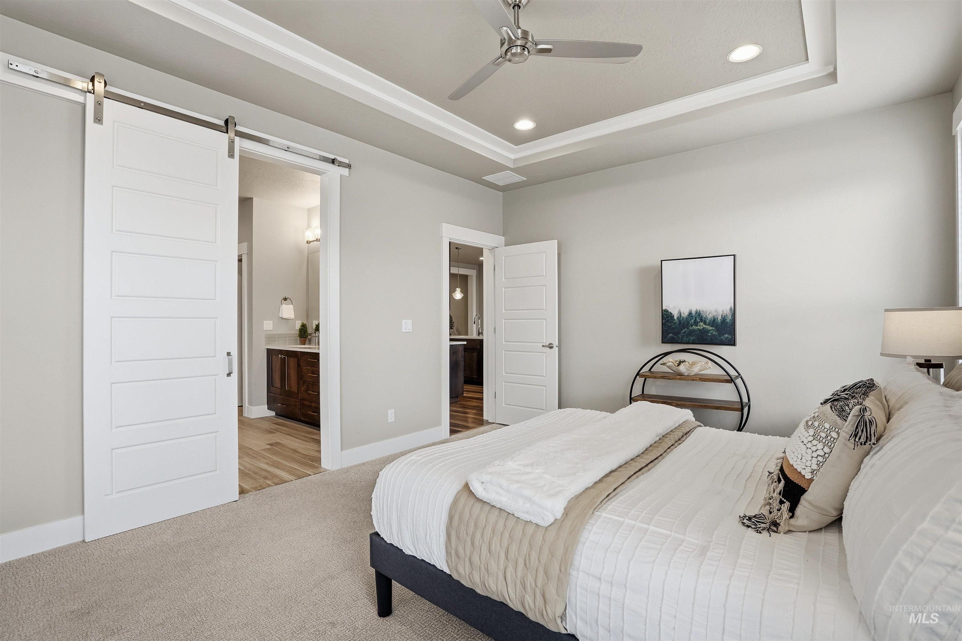 8087 Tandy Cove Street Middleton, ID 83644 - Photo 20 of 50 Bedroom with light carpet, recessed lighting, a tray ceiling, connected bathroom, and a ceiling fan