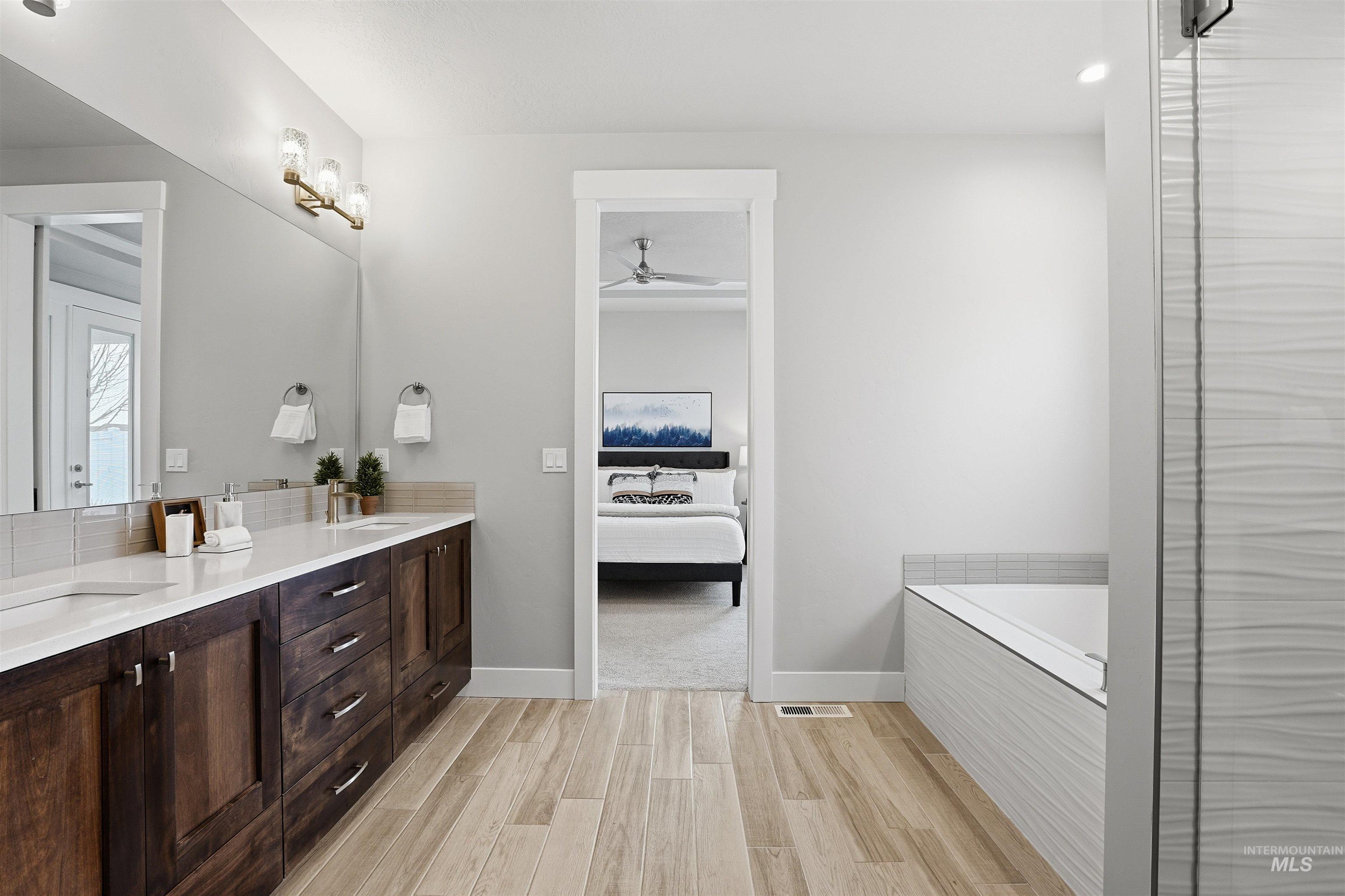 8087 Tandy Cove Street Middleton, ID 83644 - Photo 24 of 50 Ensuite bathroom featuring wood finish floors, double vanity, a bath, a ceiling fan, and a shower with shower door