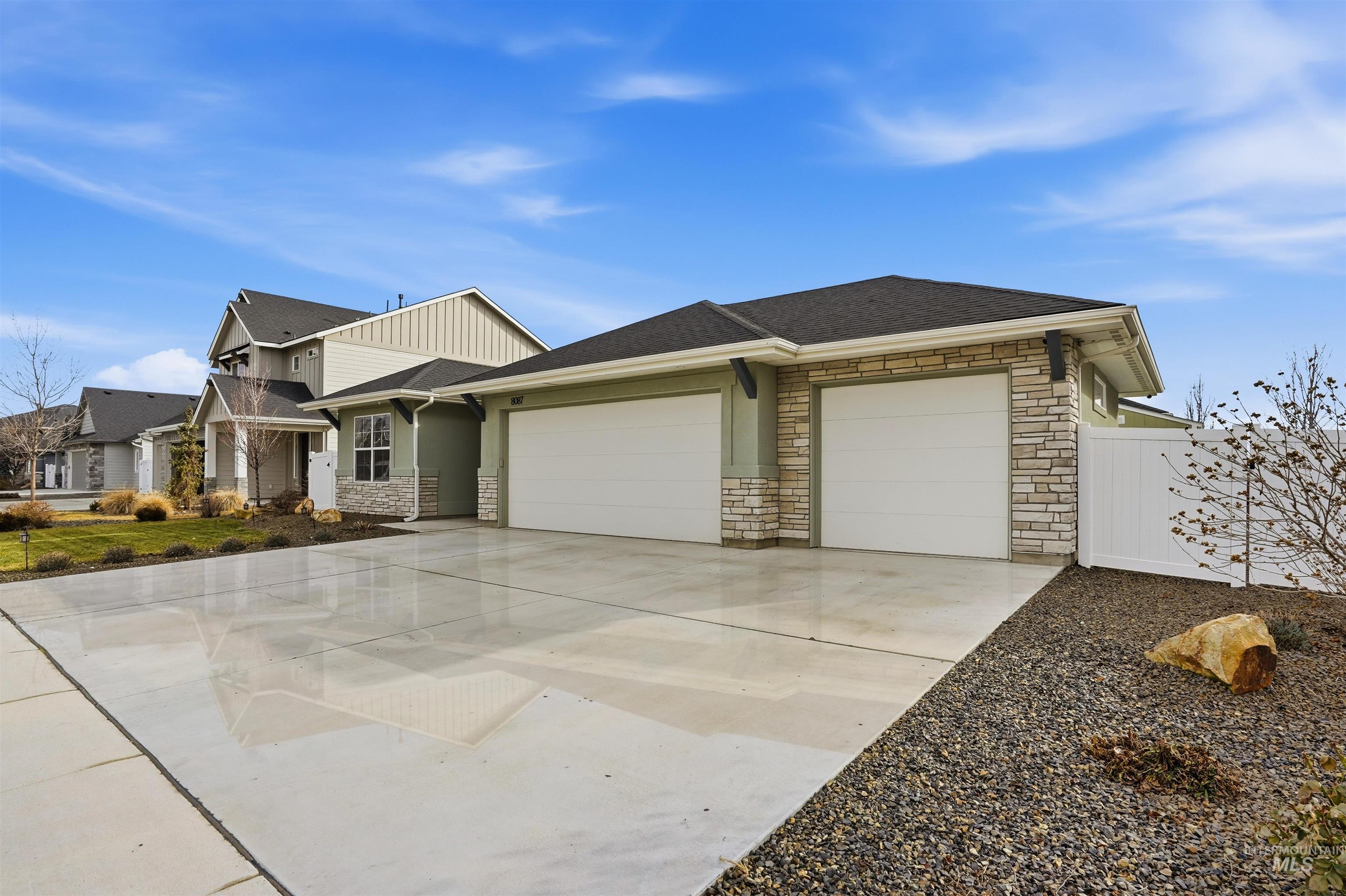 8087 Tandy Cove Street Middleton, ID 83644 - Photo 47 of 50 View of front of house with stone siding, an attached garage, driveway, a shingled roof, and board and batten siding