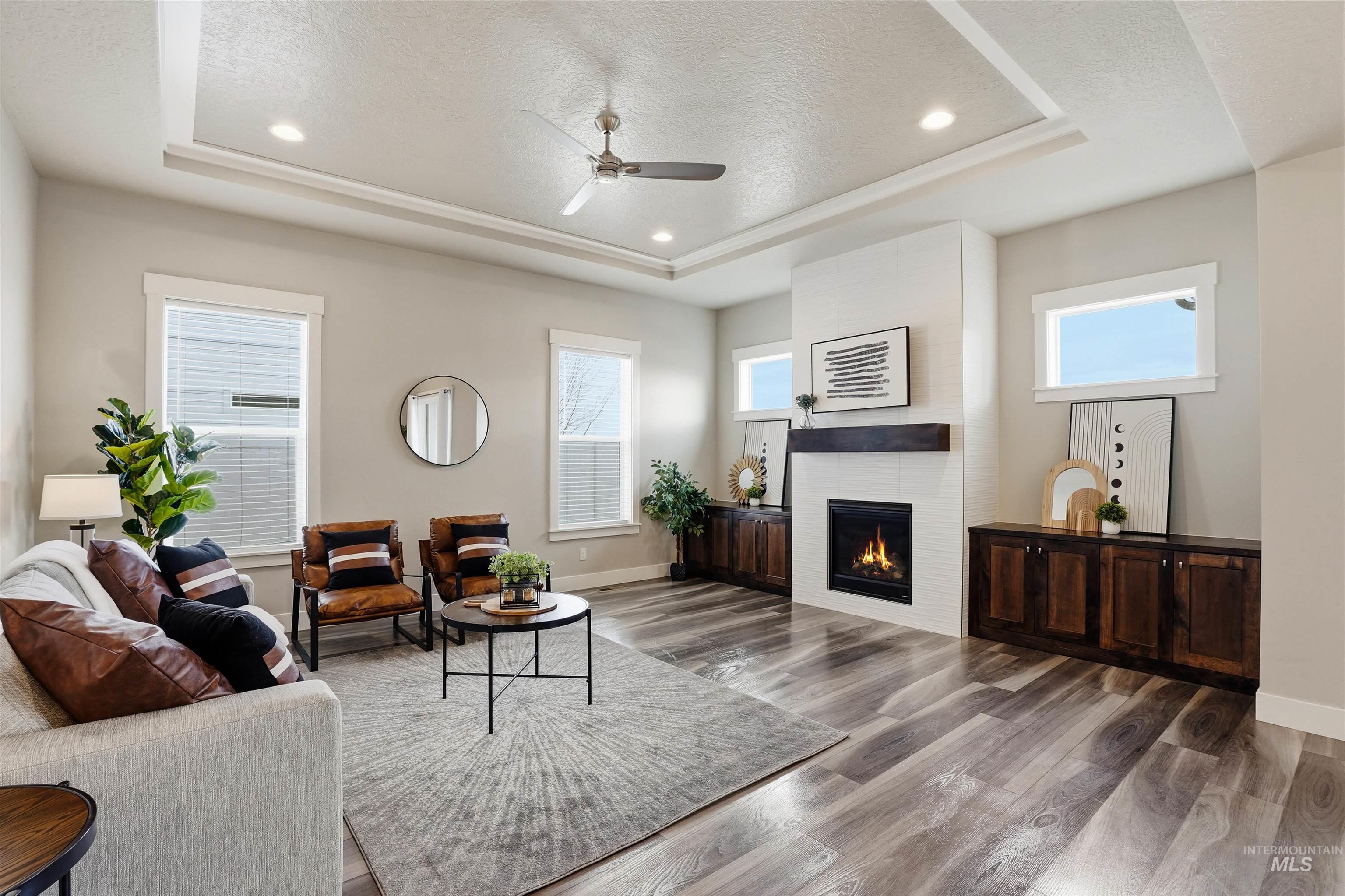 8087 Tandy Cove Street Middleton, ID 83644 - Photo 6 of 50 Living room featuring ceiling fan, healthy amount of natural light, a large fireplace, recessed lighting, and a tray ceiling