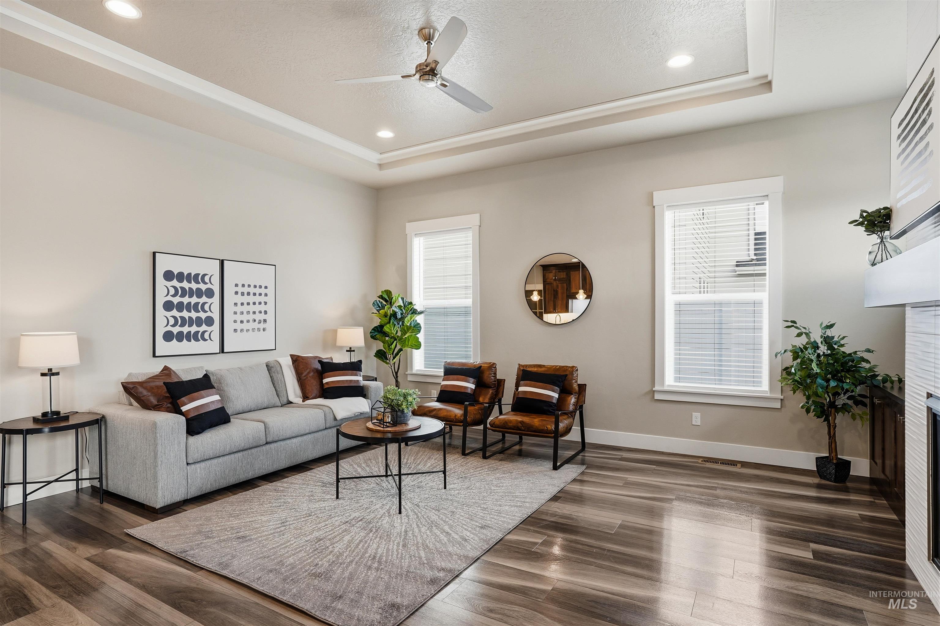 8087 Tandy Cove Street Middleton, ID 83644 - Photo 8 of 50 Living area with dark wood-style floors, a ceiling fan, a fireplace, recessed lighting, and a raised ceiling