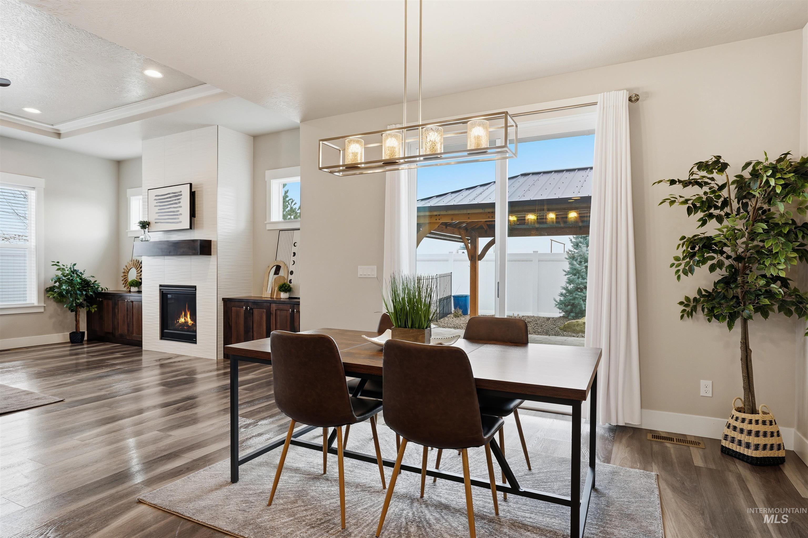 8087 Tandy Cove Street Middleton, ID 83644 - Photo 10 of 50 Dining room with a glass covered fireplace, a tray ceiling, dark wood-type flooring, healthy amount of natural light, and recessed lighting