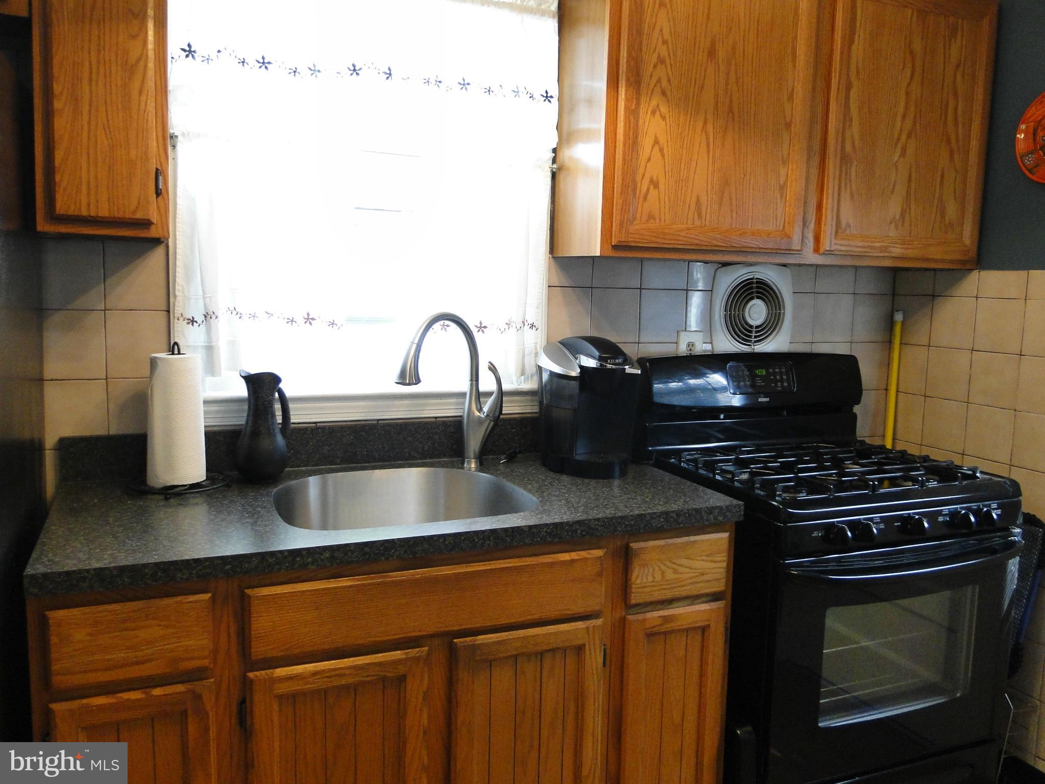 8419 Oakleigh Road Baltimore, MD 21234 - Photo 18 of 30 a kitchen with sink a stove and cabinets