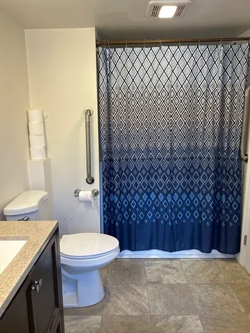 a bathroom with a granite countertop toilet and a shower