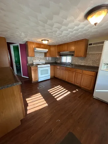 a kitchen with stainless steel appliances granite countertop a sink stove and wooden cabinets