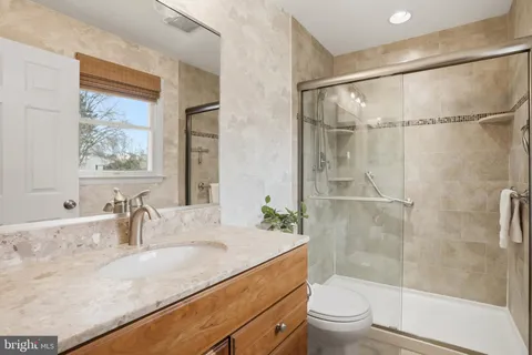 a bathroom with a granite countertop sink toilet and shower