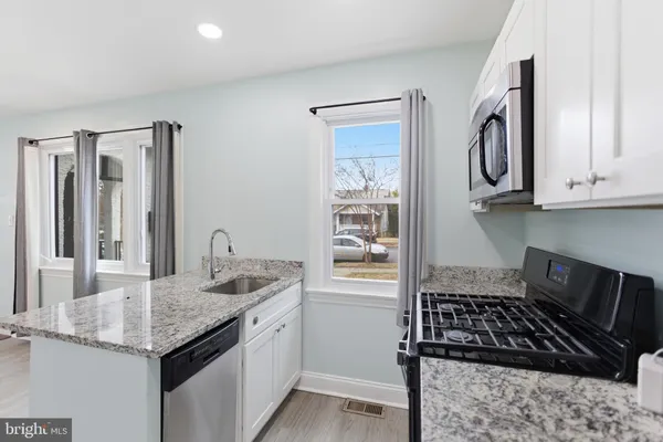 a kitchen with granite countertop a sink stove and cabinets