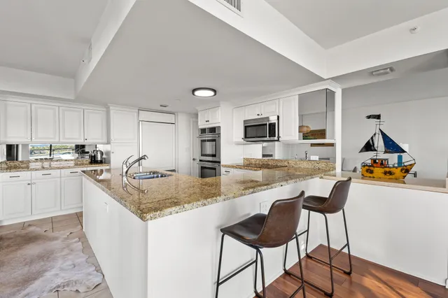 a large kitchen with granite countertop a large counter top stainless steel appliances and cabinets