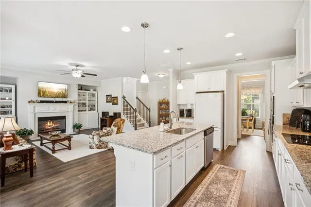 a large kitchen with stainless steel appliances kitchen island granite countertop a sink refrigerator and a wooden floor