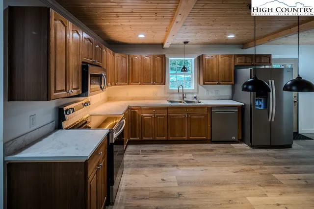 a kitchen with stainless steel appliances granite countertop a sink a stove and a wooden floors
