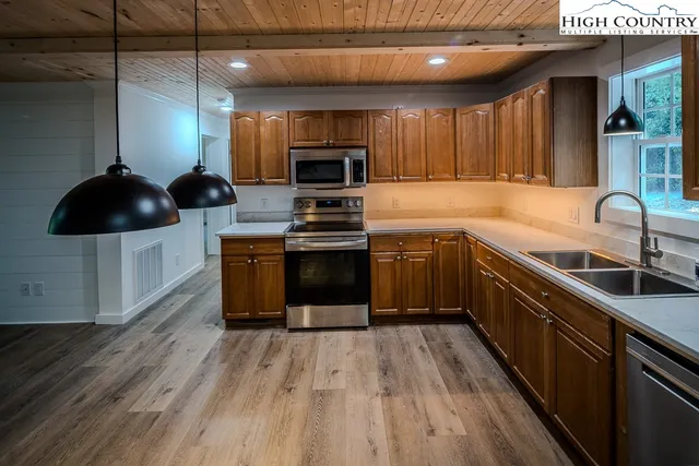 a kitchen with stainless steel appliances kitchen island granite countertop a sink a stove top oven a counter space and cabinets