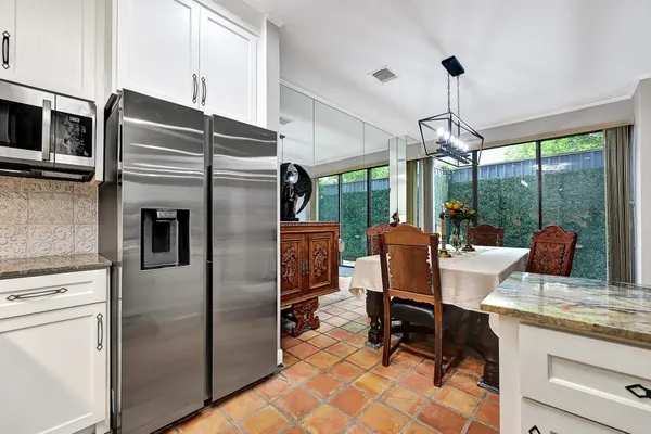 a kitchen with stainless steel appliances granite countertop a refrigerator a stove and a chandelier