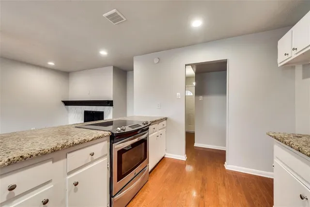 a kitchen with granite countertop cabinets stainless steel appliances and wooden floor