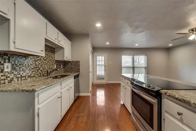 a kitchen with granite countertop a sink stove and cabinets