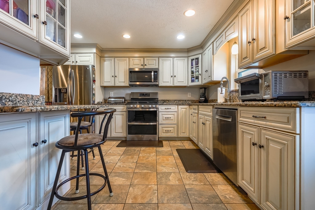 142 Norman Street Fall River, MA 02721 - Photo 4 of 25 a kitchen with kitchen island granite countertop a stove top oven a sink a counter space and cabinets