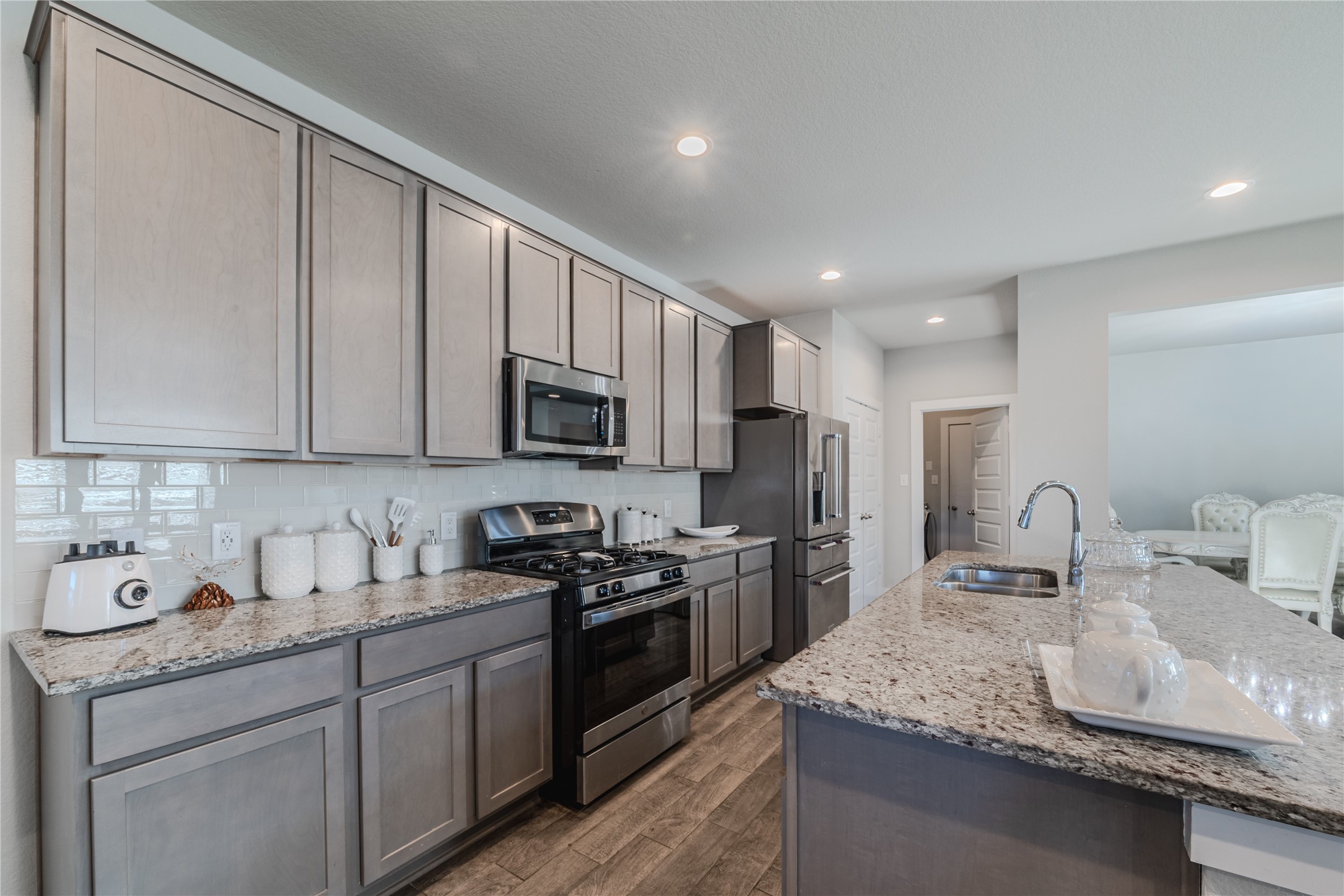 4259 Wyanngate Drive Spring, TX 77373 - Photo 15 of 46 Modern kitchen equipped with stainless steel appliances and elegant grey cabinetry, opening directly into a sunlit breakfast nook