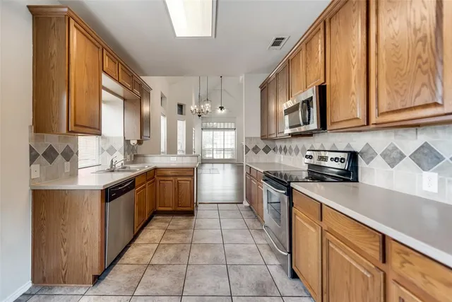 a large kitchen with stainless steel appliances granite countertop a stove a sink dishwasher and a refrigerator
