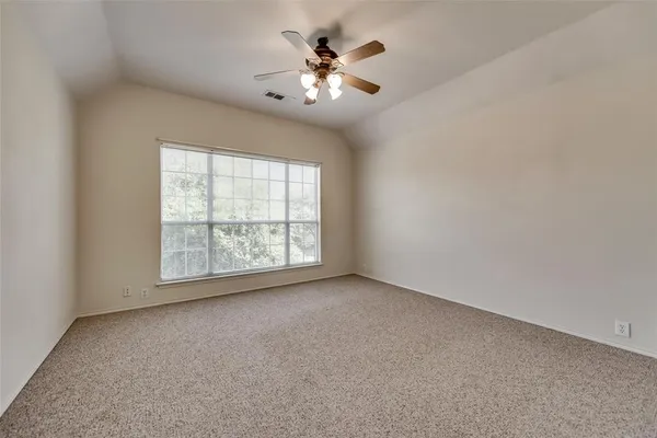 an empty room with chandelier fan and windows