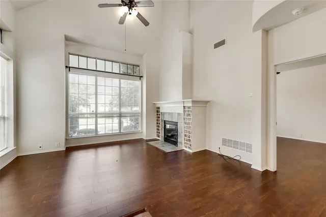 an empty room with wooden floor chandelier and windows