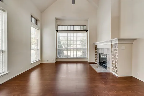 an empty room with wooden floor fireplace and windows