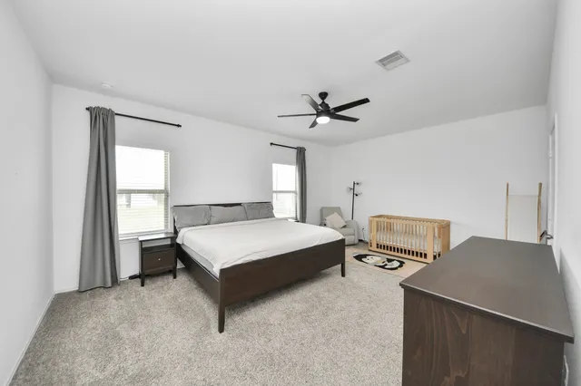 a bedroom with a bed a computer on a desk and a printer next to a window