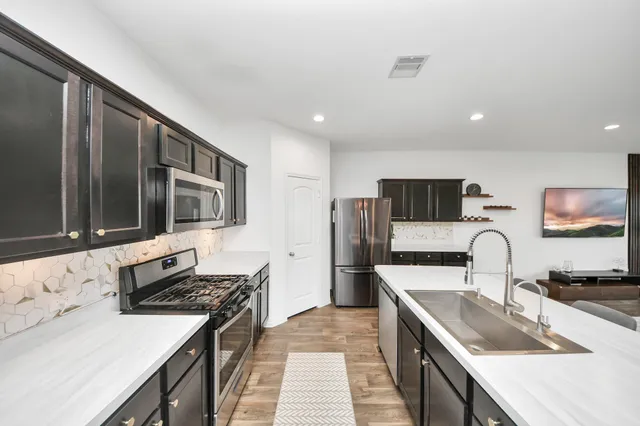 a kitchen with stainless steel appliances a stove a sink a microwave a refrigerator and cabinets