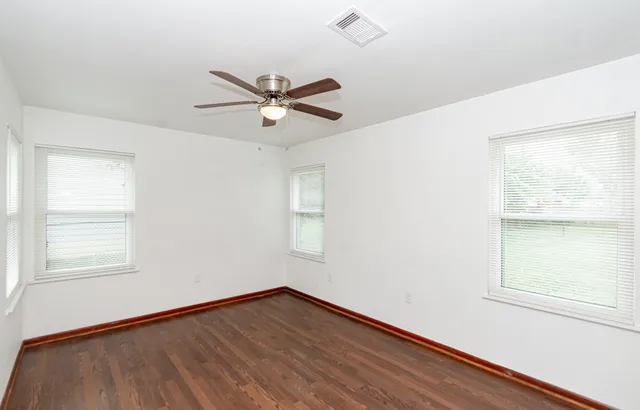 a view of empty room with wooden floor and fan