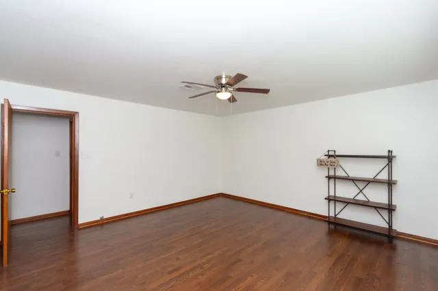 a view of a room with wooden floor and a ceiling fan