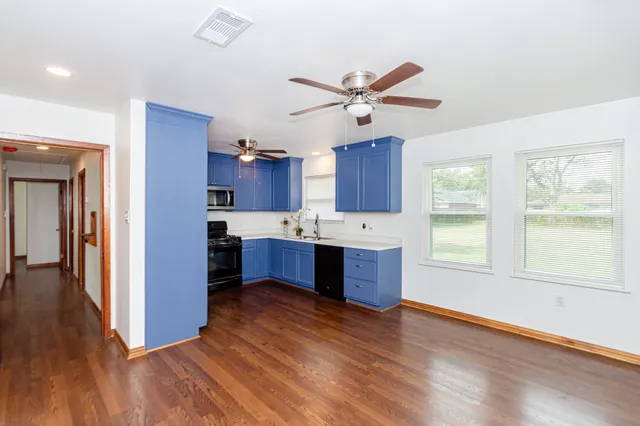 a view of kitchen with stainless steel appliances granite countertop a stove a sink and a refrigerator with wooden floors