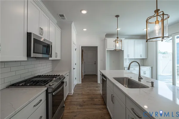 a kitchen with stainless steel appliances granite countertop a sink a stove and a refrigerator