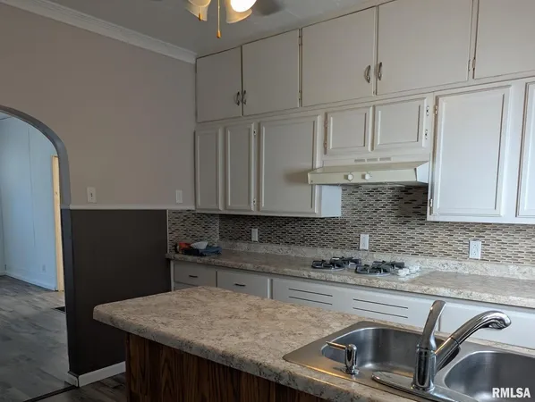 a kitchen with granite countertop a sink a stove and cabinets