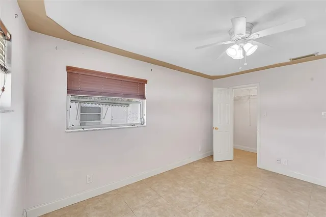 a view of an empty room with wooden floor and a ceiling fan