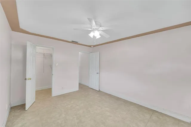 an empty room with closet and a ceiling fan