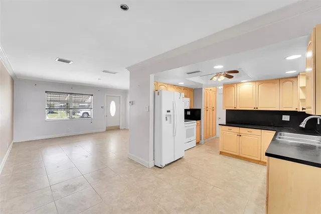 a view of a kitchen with a sink and dishwasher a refrigerator with white cabinets