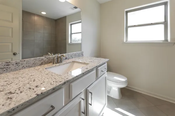 a bathroom with a granite countertop sink a toilet and a window