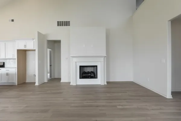 a view of an empty room with wooden floor fireplace and a window