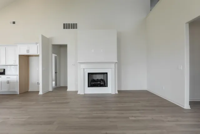 a view of an empty room with wooden floor fireplace and a window
