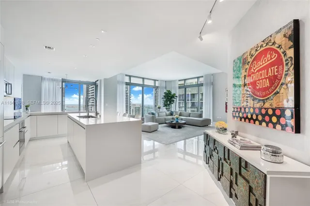 a large white kitchen with a large window and stainless steel appliances