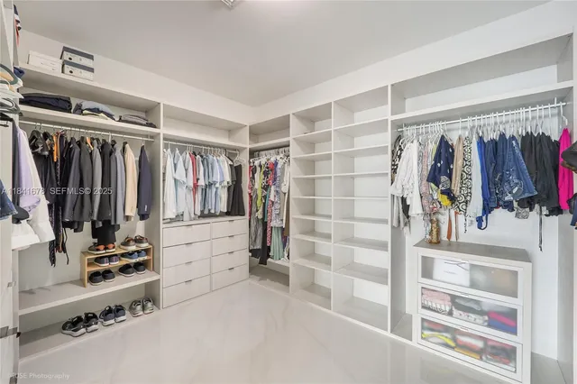 a view of walk in closet with clothes and shoes