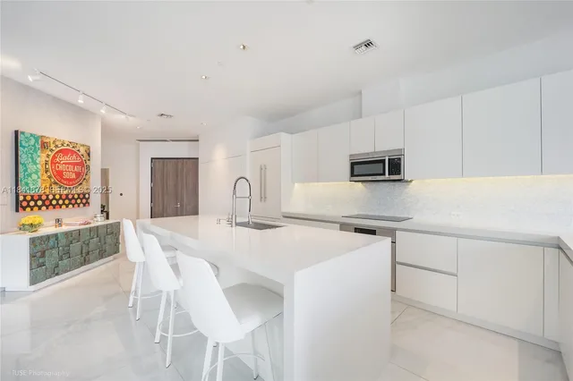 a kitchen with stainless steel appliances a white table chairs and a refrigerator