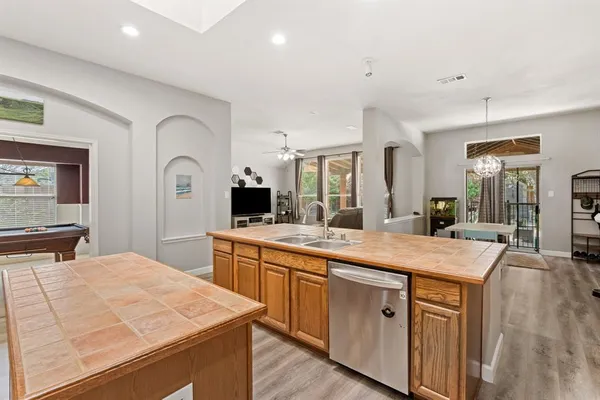 a large kitchen with stainless steel appliances kitchen island a stove a sink dishwasher and white cabinets with wooden floor