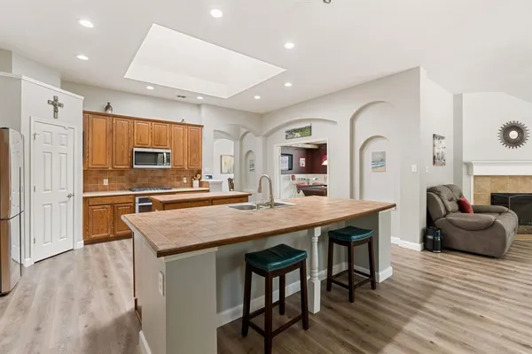 a kitchen with stainless steel appliances granite countertop a table chairs refrigerator and sink