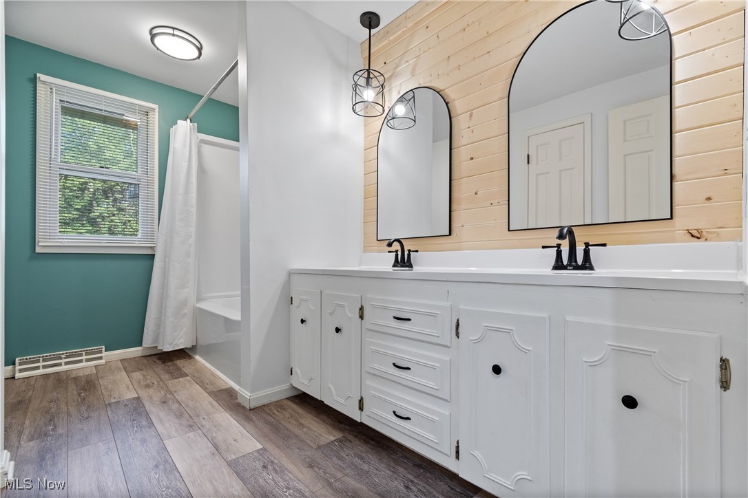 515 Oneida Avenue Northwest Canton, OH 44708 - Photo 19 of 28 Full bathroom with shower / bath combo with shower curtain, double vanity, dark wood-style floors, and wooden walls