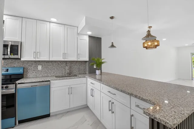 a kitchen with a white cabinets and chandelier