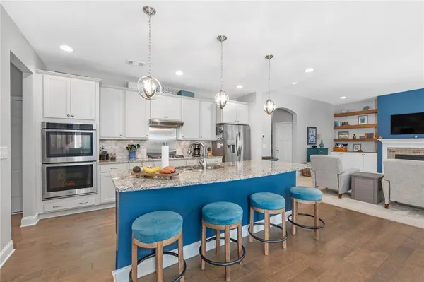 a kitchen with stainless steel appliances granite countertop a refrigerator sink and white cabinets