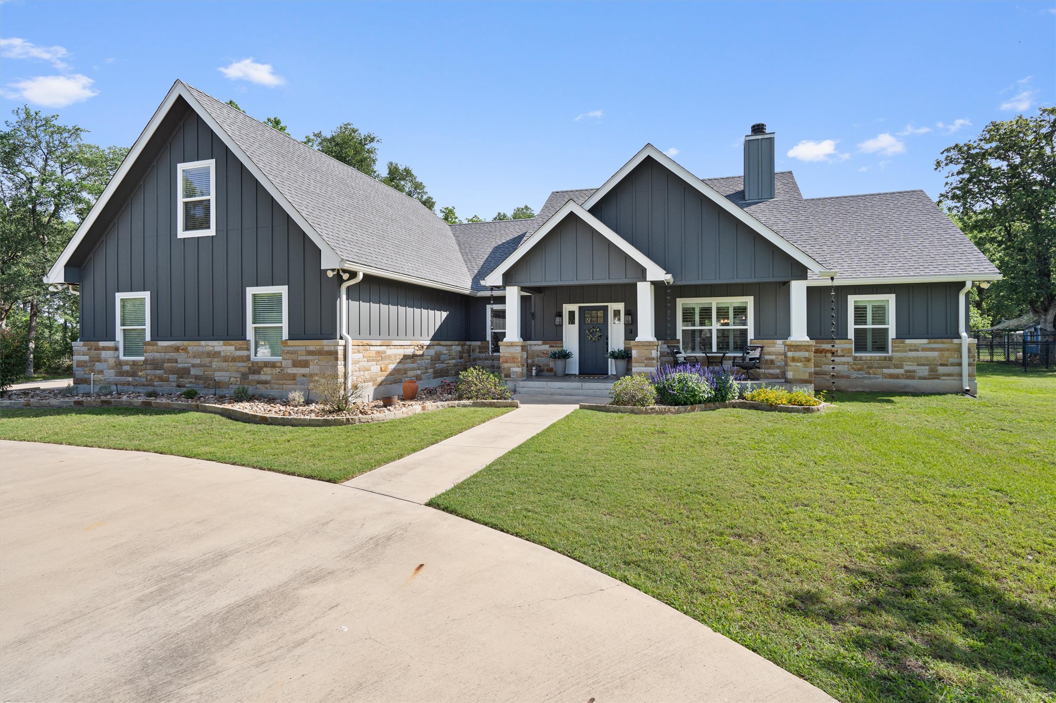 Contemporary-style home featuring dark gray vertical siding and a stone facade