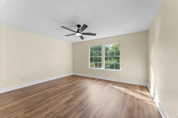 an empty room with wooden floor and windows